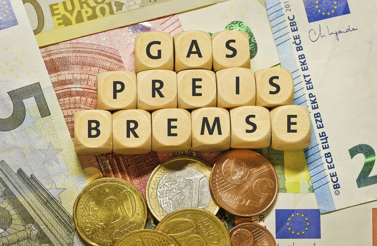 The word "Gaspreisdeckel" in german language, on a stack of euro banknootes and coins. The energy crisis is driving the cost of gas to unprecedented heights. Governments introduce financial support (gas price cap) for end consumers and companies.