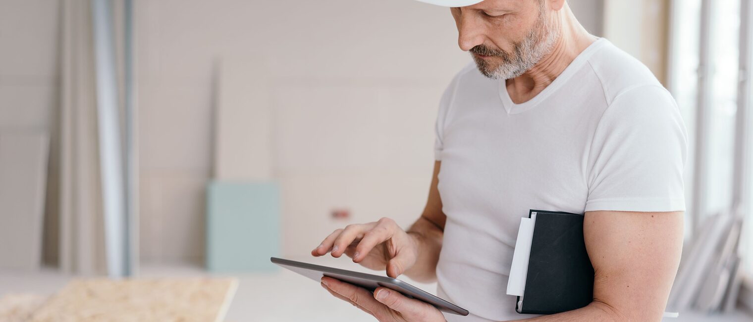 Seriöser Baumeister, der etwas auf einem Tablet überprüft