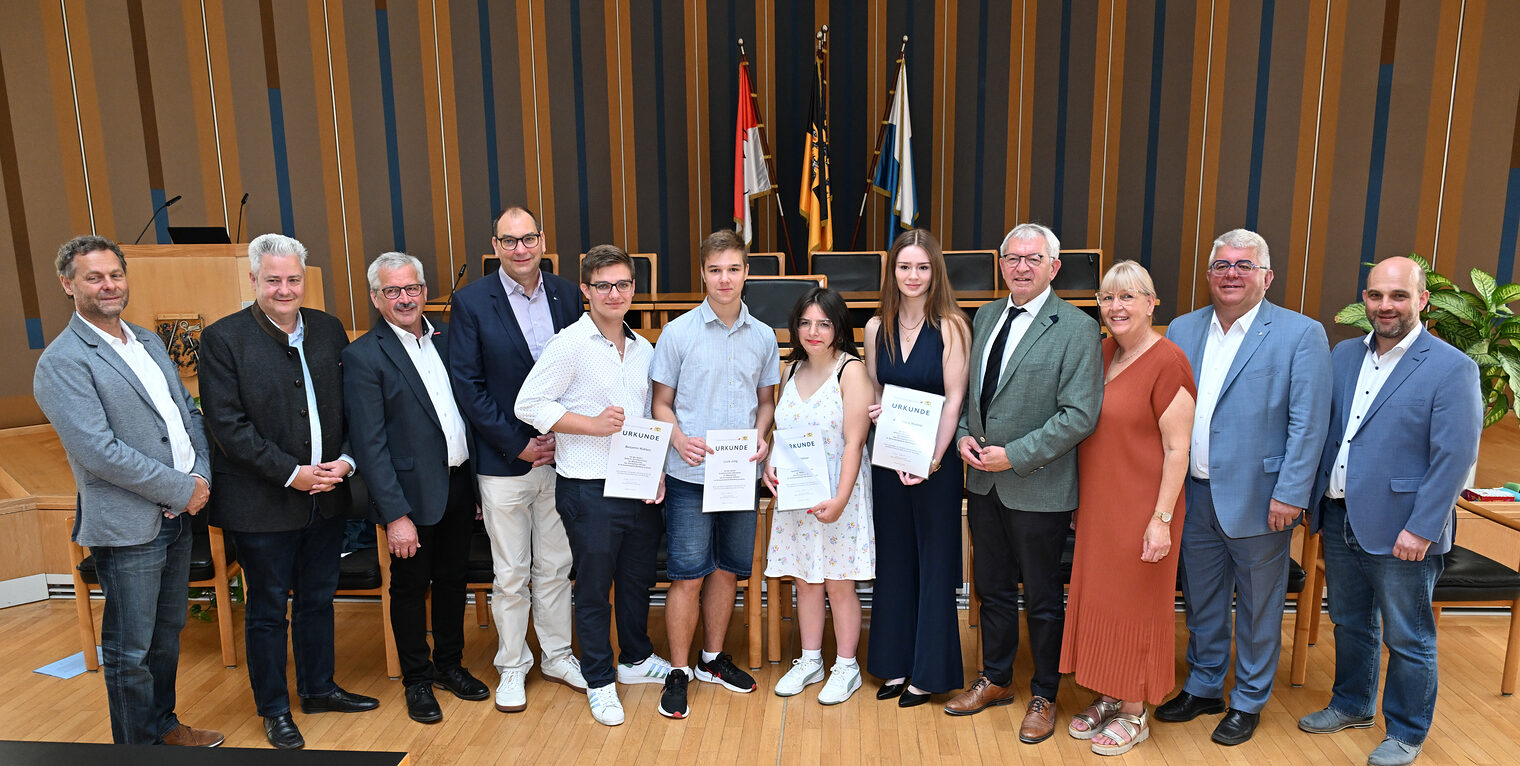 Gruppenfoto von Schülern mit Urkunden und Lehrern und Vertretern bei der Bestenehrung in einem festlichen Saal.