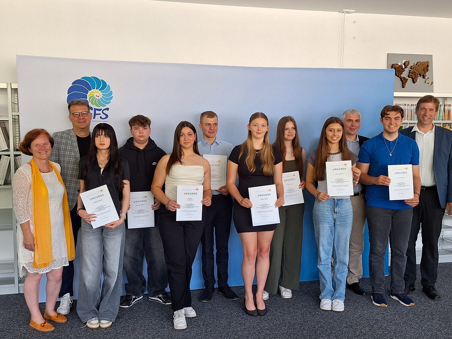 Gruppenfoto von Schülern mit Urkunden und Lehrern bei der Bestenehrung 2024 vor einem Banner