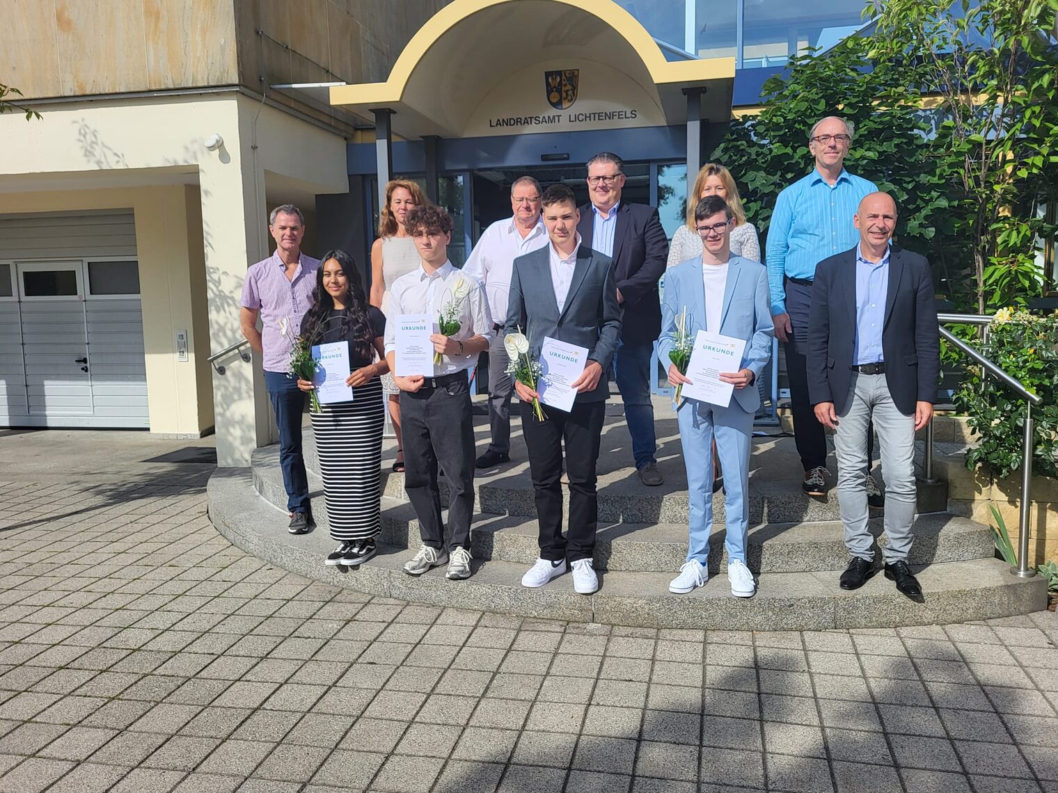 Gruppenfoto von Schülern mit Urkunden und Blumen sowie Lehrern bei der Bestenehrung 2024 vor dem Landratsamt Lichtenfels.