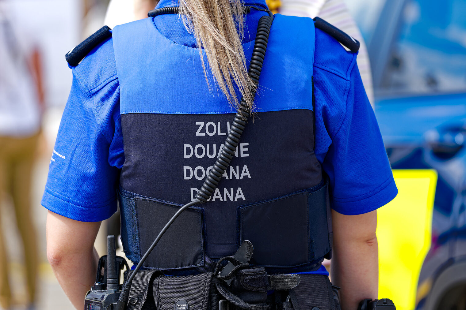 Eine Zollbeamtin mit Warnweste mit dem Aufdruck Zoll in mehreren Sprachen steht zum Einsatz bereit.