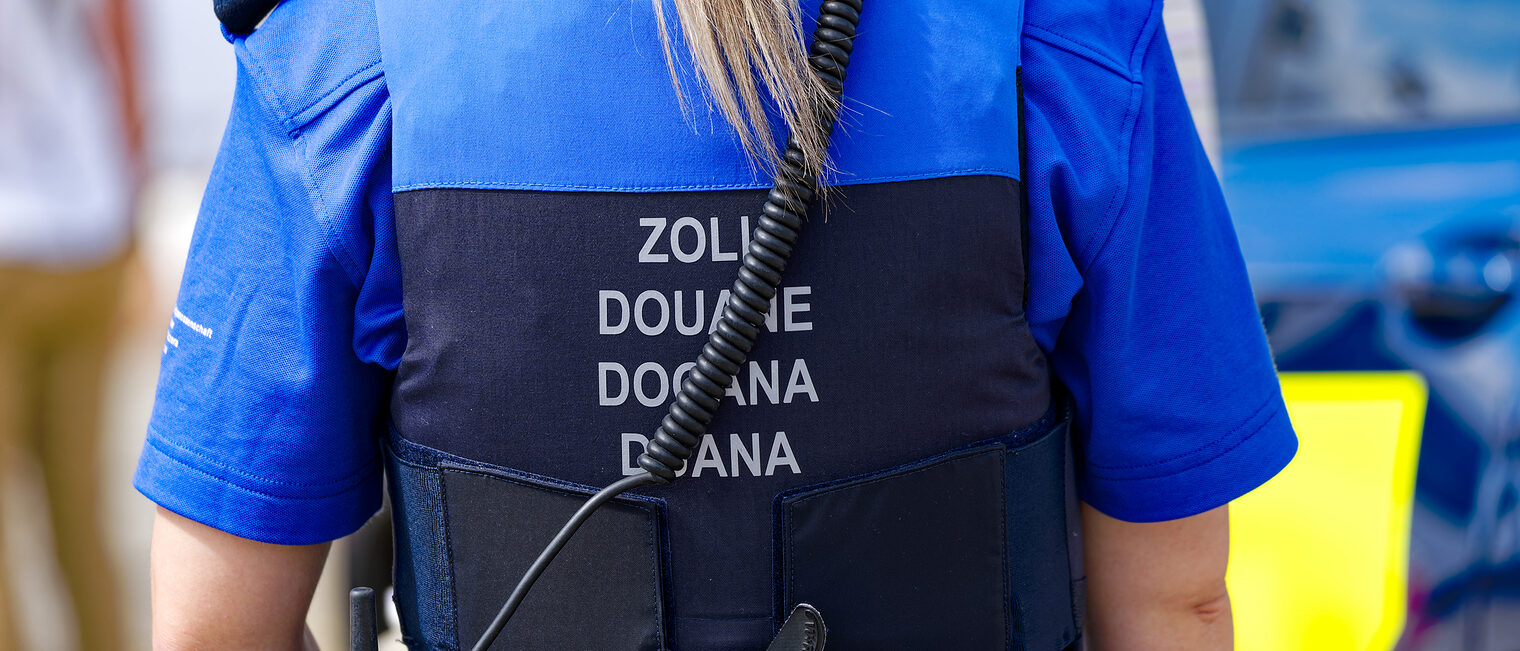 Eine Zollbeamtin mit Warnweste mit dem Aufdruck Zoll in mehreren Sprachen steht zum Einsatz bereit.