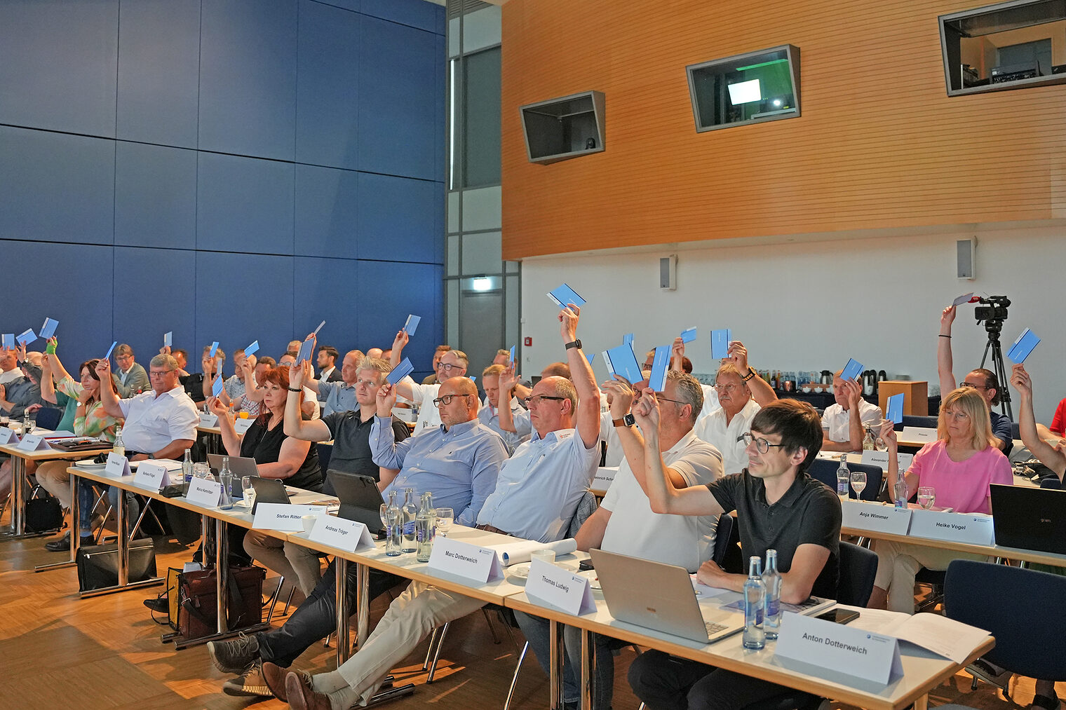 Mitglieder der Vollversammlung der Handwerkskammer für Oberfranken stimmen in einem Sitzungssaal per Handzeichen ab.