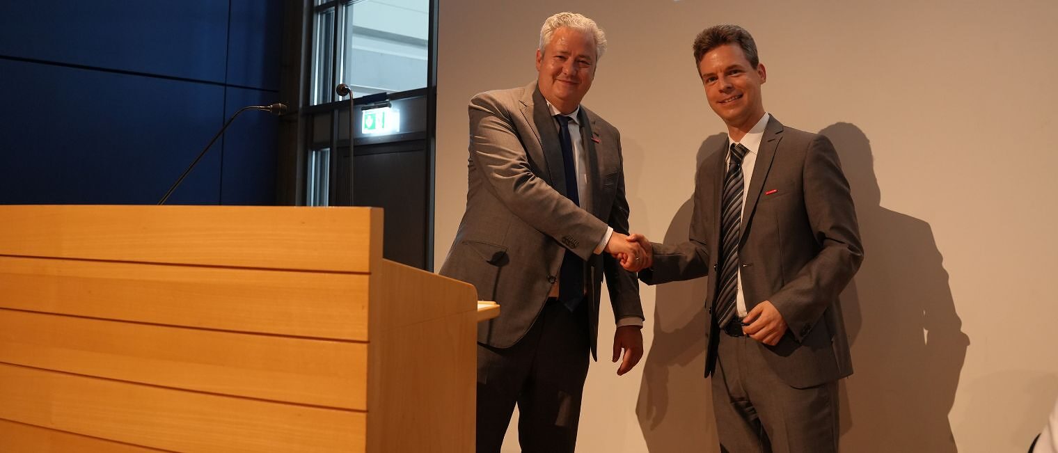 Präsident Graßmann schüttelt dem neuen Geschäftsführer Sebastian Serfas die Hand.