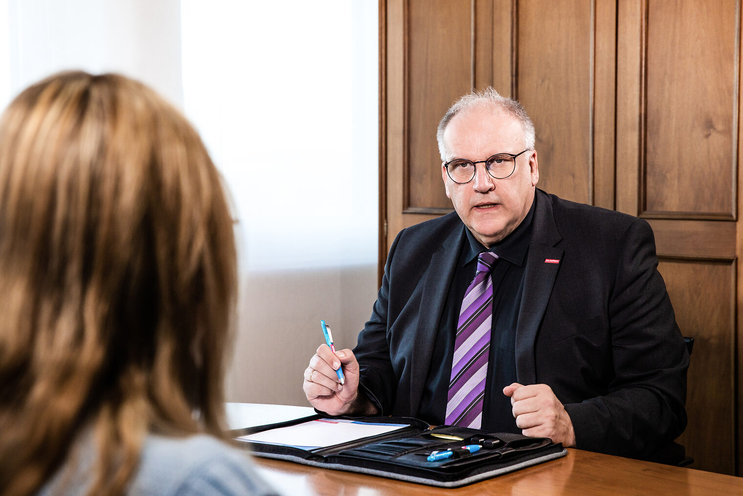 Matthias Graßmann sitzt mit Unterlagen an einem Tisch.