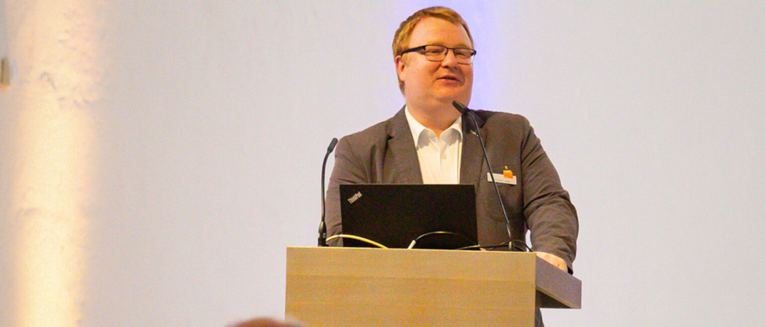 Johannes Lange spricht am Rednerpult zum Publikum.