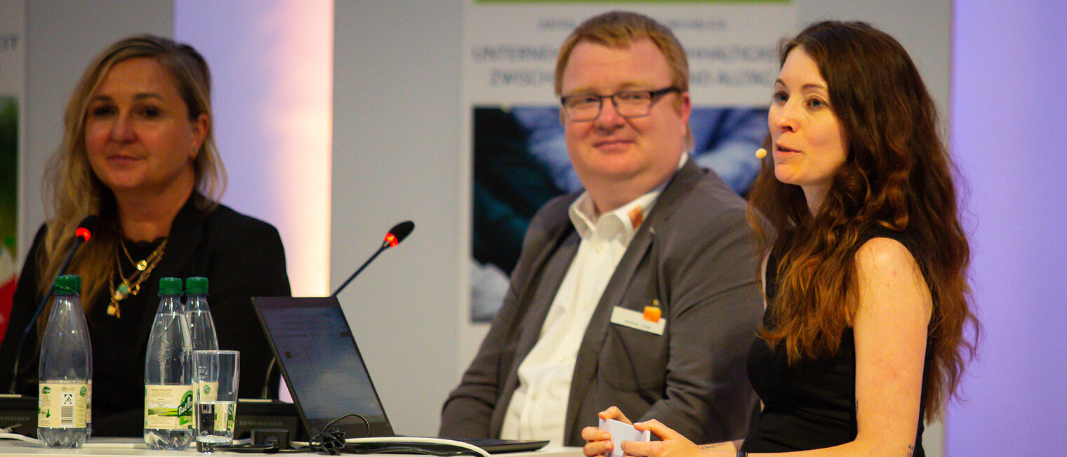 Nicole Wagner und Johannes Lange hören der Moderation von Sandra Peter zu.