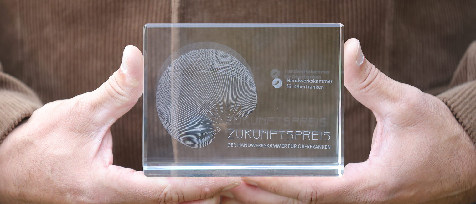 Eine Person hält die Trophäe des Zukunftspreises 2025 in den Händen. 