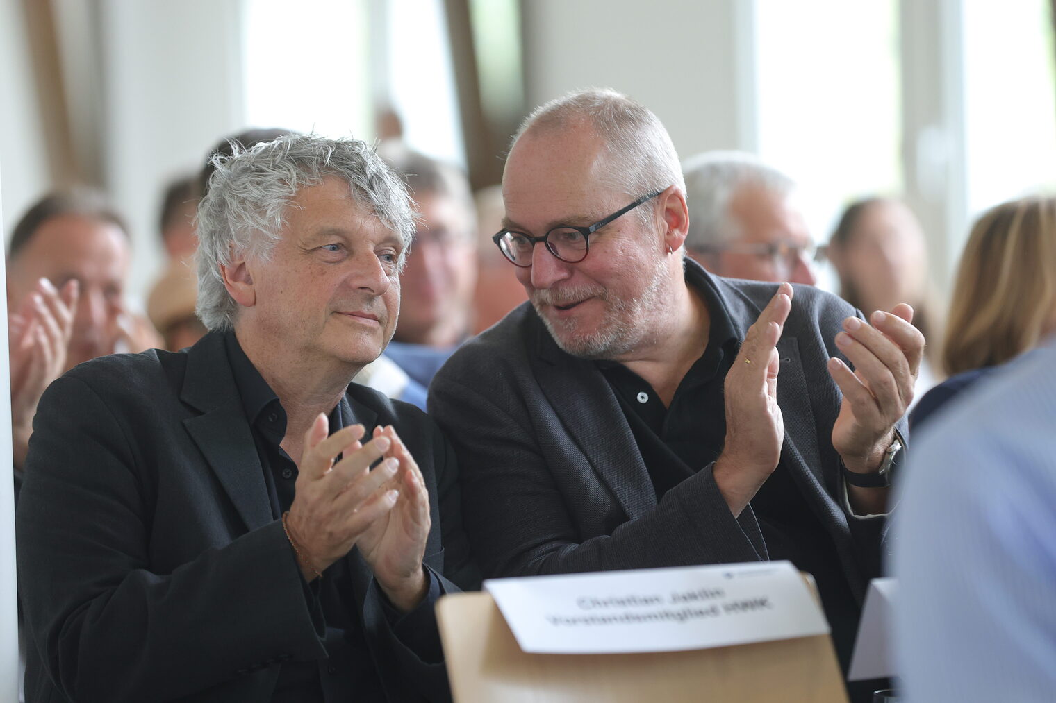 Zwei Gäste des Zukunftspreises applaudieren.