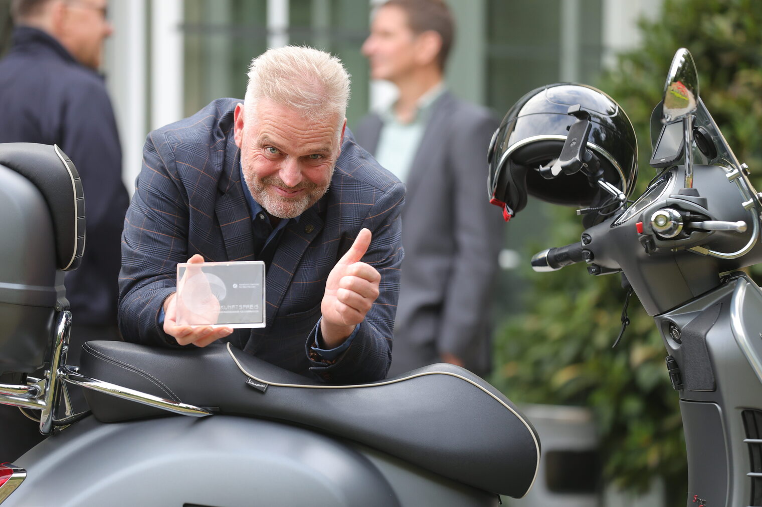 Wolfgang Fösel präsentiert an seiner Vespa seinen Zukunftspreis.