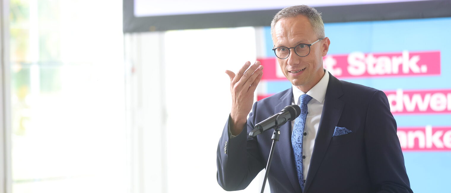 VR-Bank-Vorsitzender Joachim Hausner spricht in ein Mikrofon auf der Bühne.