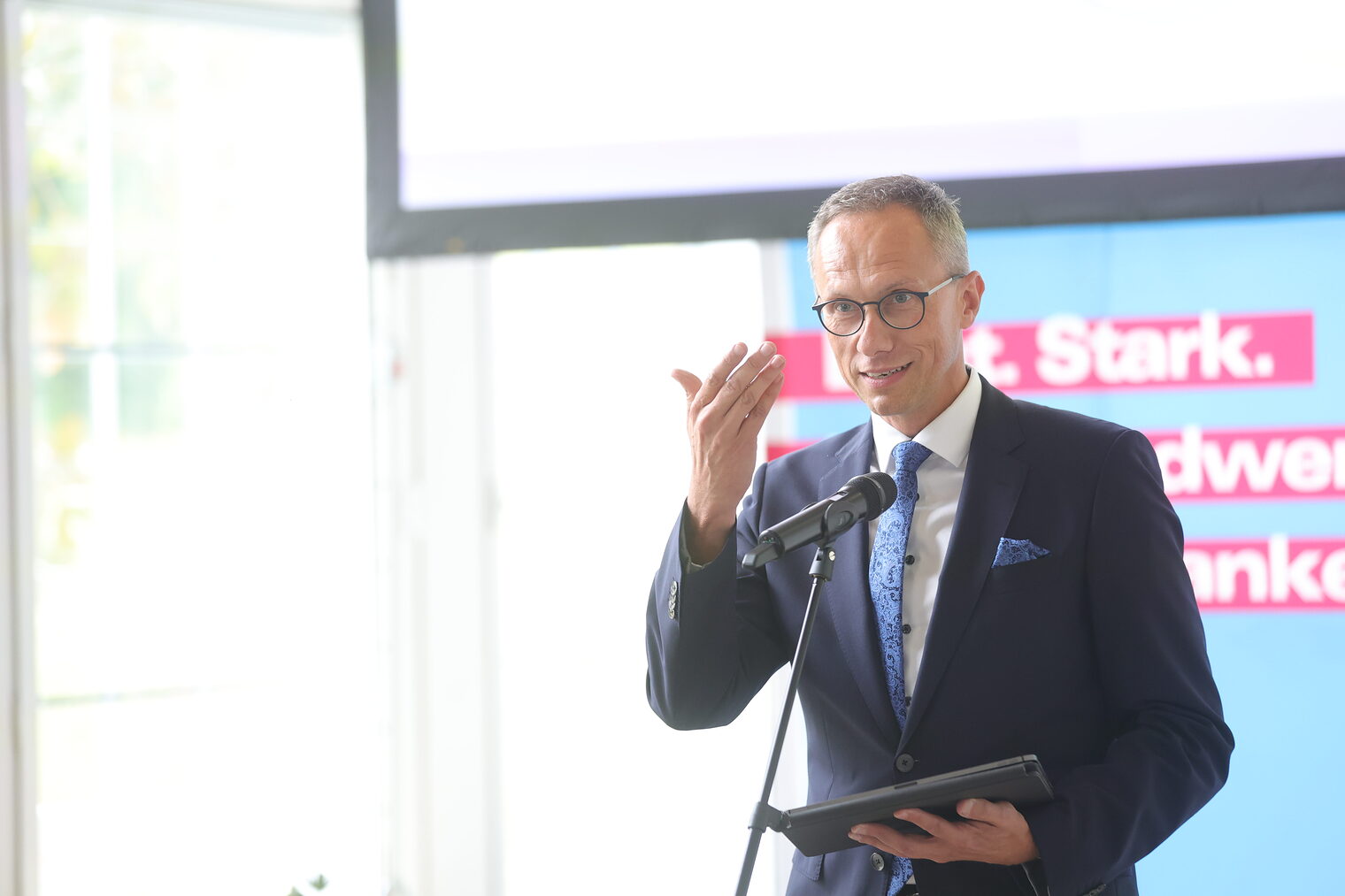 VR-Bank-Vorsitzender Joachim Hausner spricht in ein Mikrofon auf der Bühne.