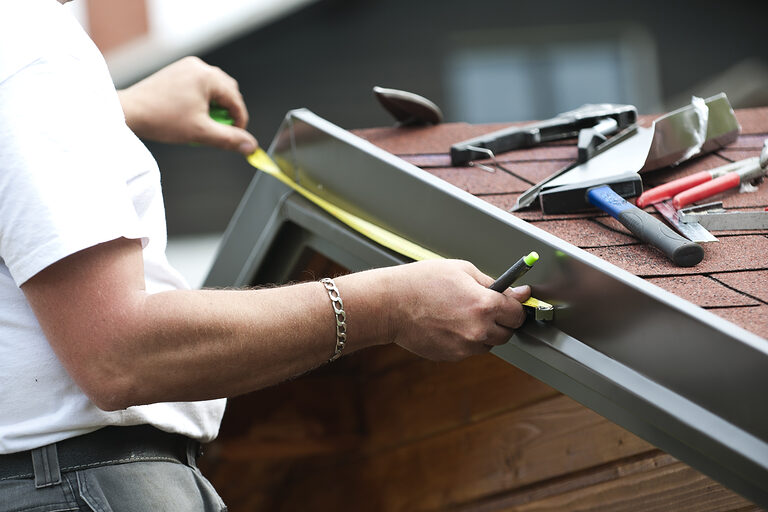 Ein Klempner vermisst die Länge einer Metallstrebe.