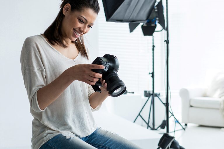 Eine Fotografin blickt in einem Fotostudio in eine Digitalkamera.