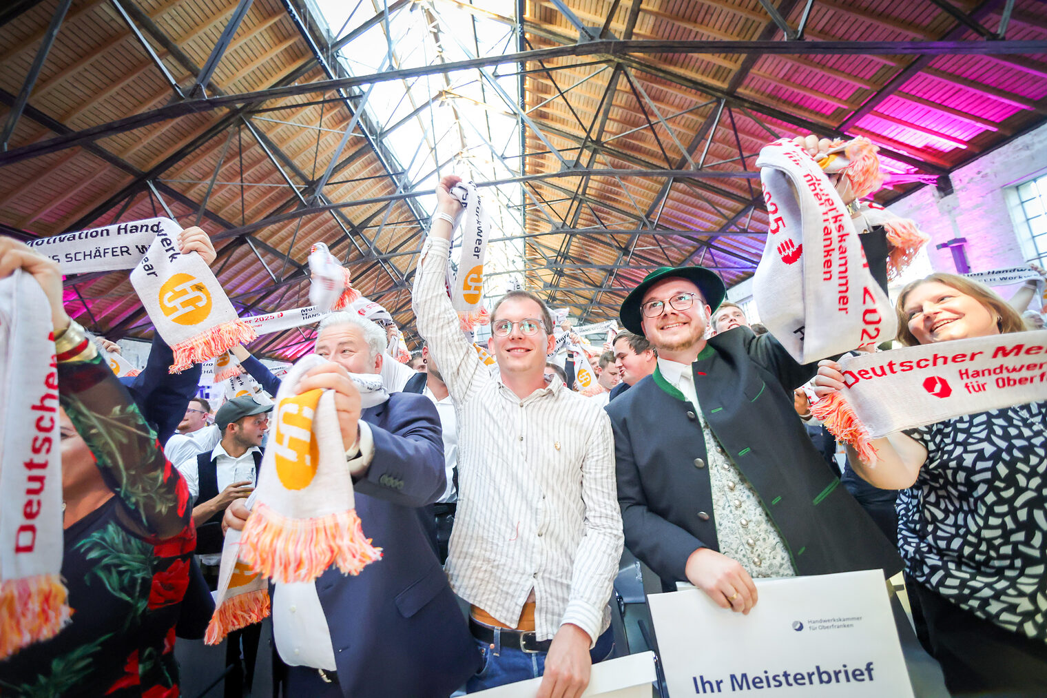 Matthias Graßmann und Meisterinnen und Meister jubeln mit ihren Meisterschals in der Glasschleif