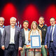 Kosmetikermeisterin Christina Schug präsentiert ihre Urkunde mit Reinhard Bauer, Matthias Graßmann, Andreas Grewe, Martin Schöffel und Ralf Moeller.