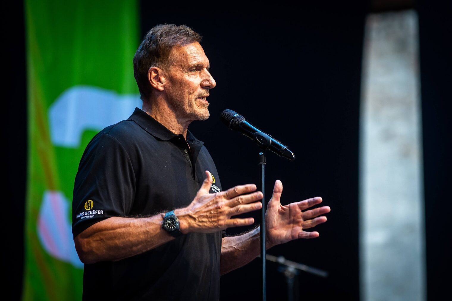 Ralf Moeller spricht auf der Bühne in ein Mikrofon.