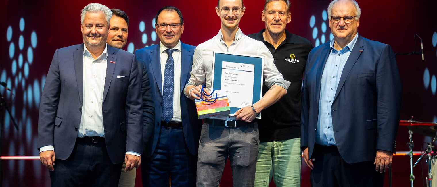 Schreinermeister David Sperber präsentiert seine Bestenurkunde mit Matthias Graßmann, Andreas Grewe, Martin Schöffel, Ralf Moeller und Reinhard Bauer.