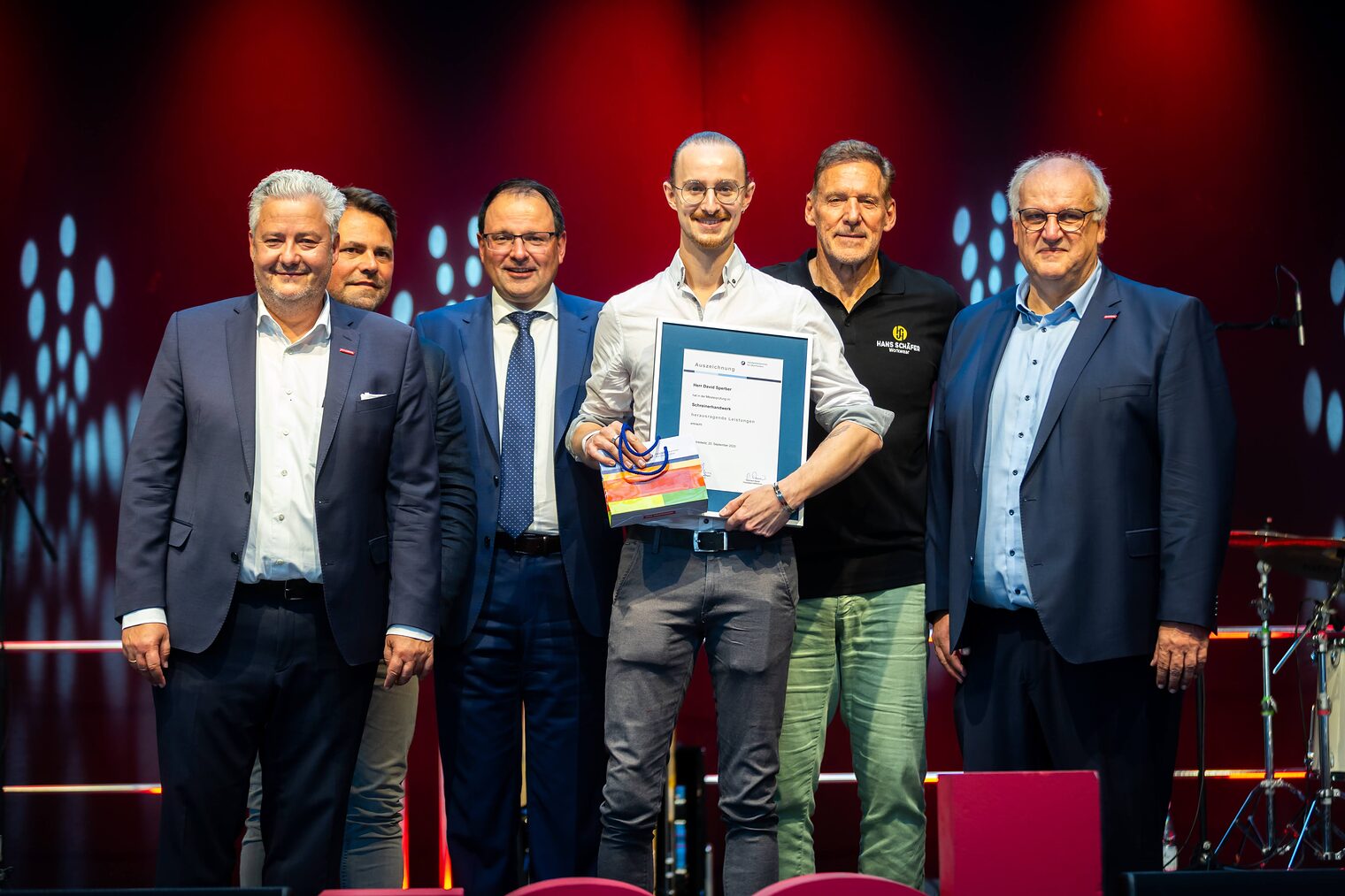 Schreinermeister David Sperber präsentiert seine Bestenurkunde mit Matthias Graßmann, Andreas Grewe, Martin Schöffel, Ralf Moeller und Reinhard Bauer.