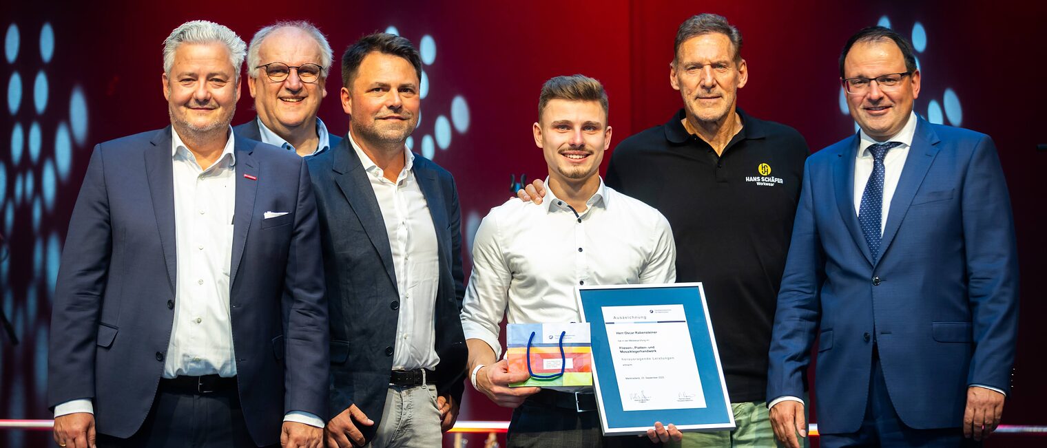 Fliesenlegermeister Oscar Rabensteiner präsentiert seine Bestenurkunde mit Matthias Graßmann, Reinhard Bauer, Andreas Grewe, Ralf Moeller, Martin Schöffel