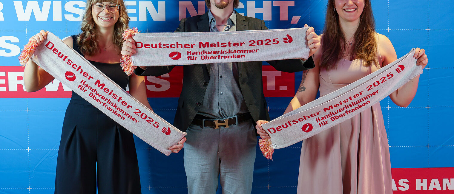 Lissi Teichmann und ihre Familie posieren mit Meisterschals vor einer Fotowand.