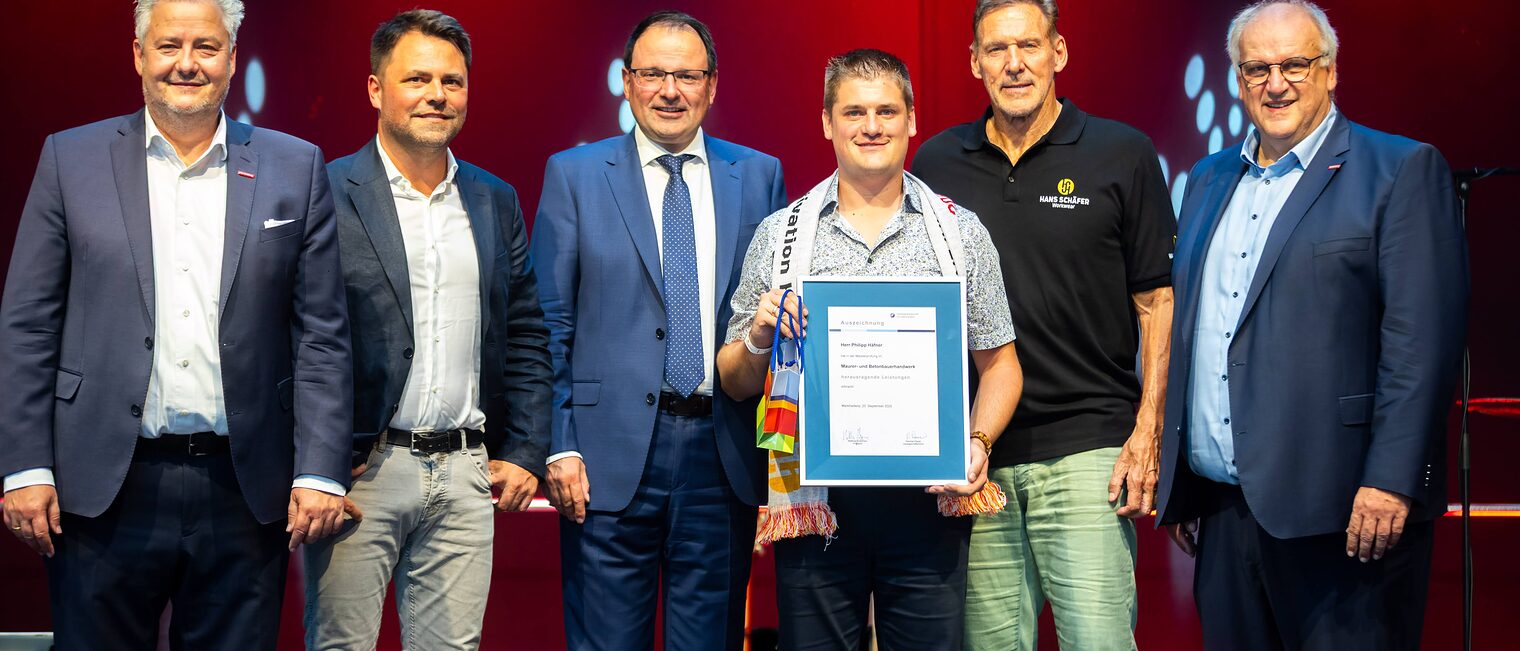 Maurer- und Betonbauermeister Philipp Häfner präsentiert seine Bestenurkunde mit Matthias Graßmann, Andreas Grewe, Martin Schöffel, Ralf Moeller und Reinhard Bauer.