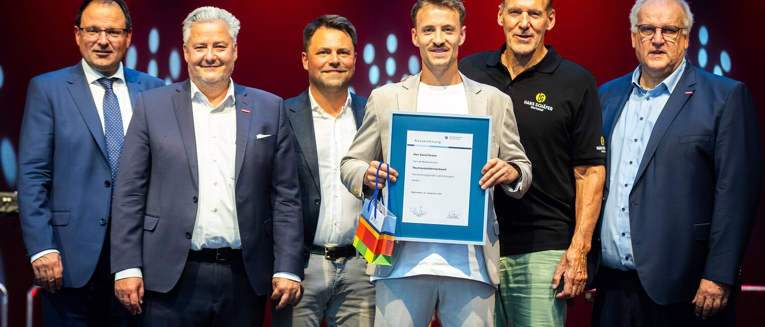 Raumaustattermeister David Kneier präsentiert seine Bestenurkunde mit Martin Schöffel, Matthias Graßmann, Andreas Grewe, Ralf Moeller und Reinhard Bauer