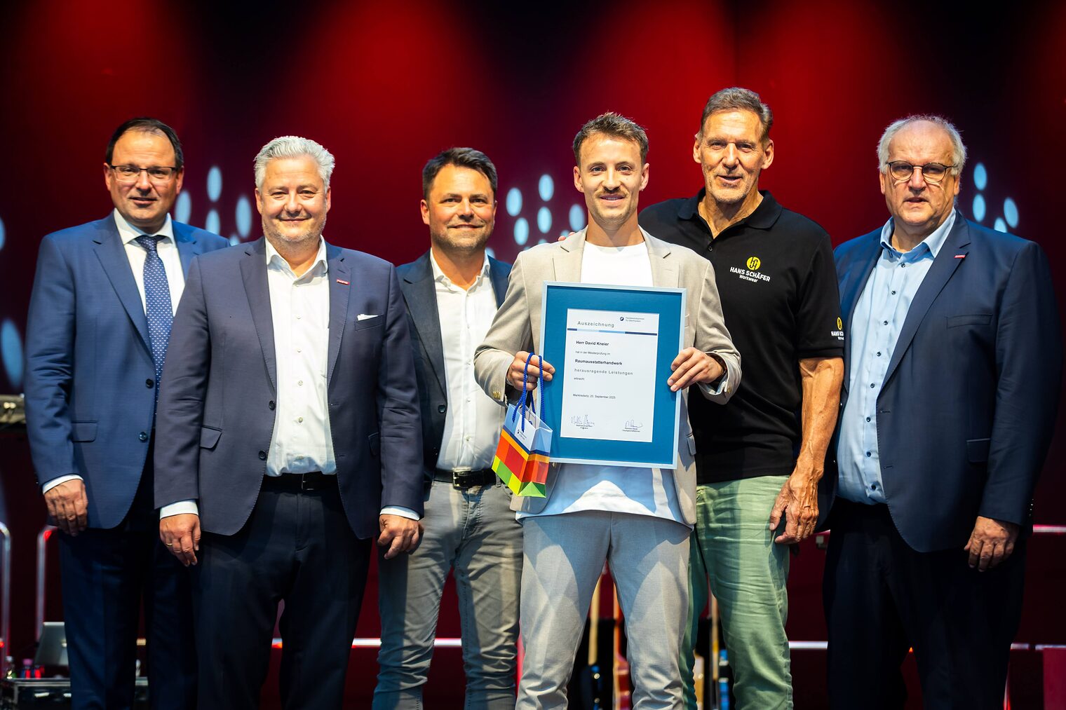 Raumaustattermeister David Kneier präsentiert seine Bestenurkunde mit Martin Schöffel, Matthias Graßmann, Andreas Grewe, Ralf Moeller und Reinhard Bauer