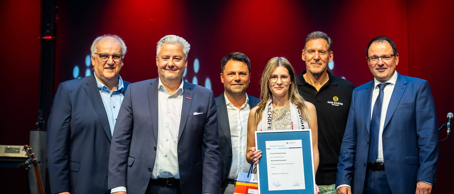 Kosmetikermeisterin Christina Schug präsentiert seine Bestenurkunde mit Martin Schöffel, Matthias Graßmann, Andreas Grewe, Ralf Moeller und Reinhard Bauer