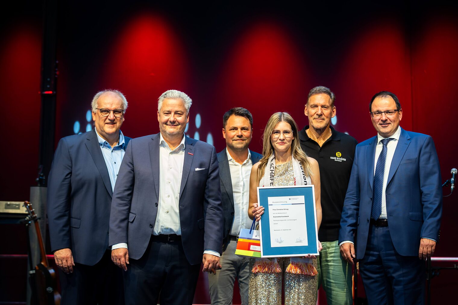 Kosmetikermeisterin Christina Schug präsentiert seine Bestenurkunde mit Martin Schöffel, Matthias Graßmann, Andreas Grewe, Ralf Moeller und Reinhard Bauer