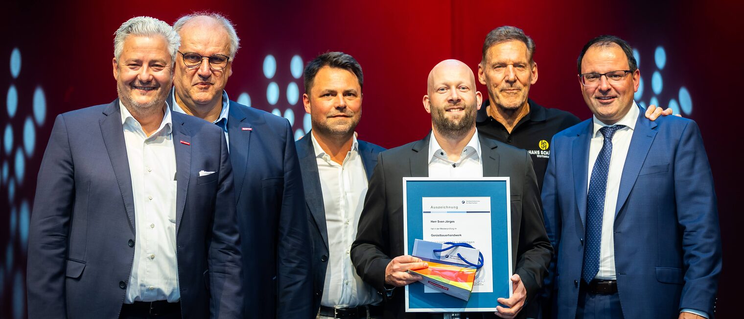 Gerüstbauermeister Sven Jörges präsentiert seine Bestenurkunde mit Matthias Graßmann, Reinhard Bauer, Andreas Grewe, Ralf Moeller und Martin Schöffel