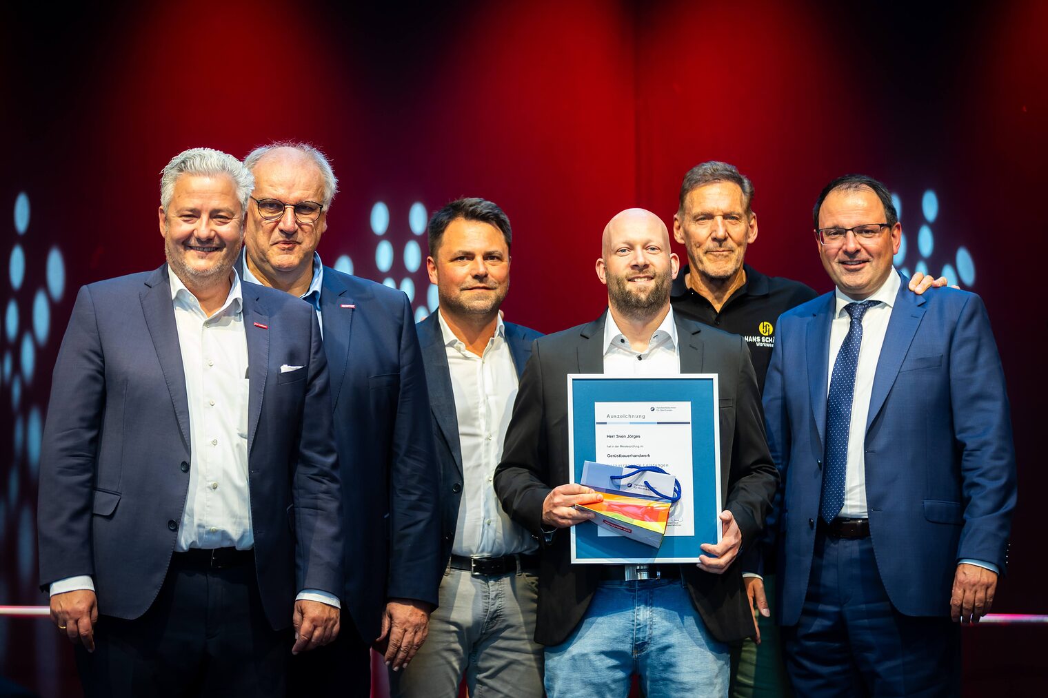 Gerüstbauermeister Sven Jörges präsentiert seine Bestenurkunde mit Matthias Graßmann, Reinhard Bauer, Andreas Grewe, Ralf Moeller und Martin Schöffel