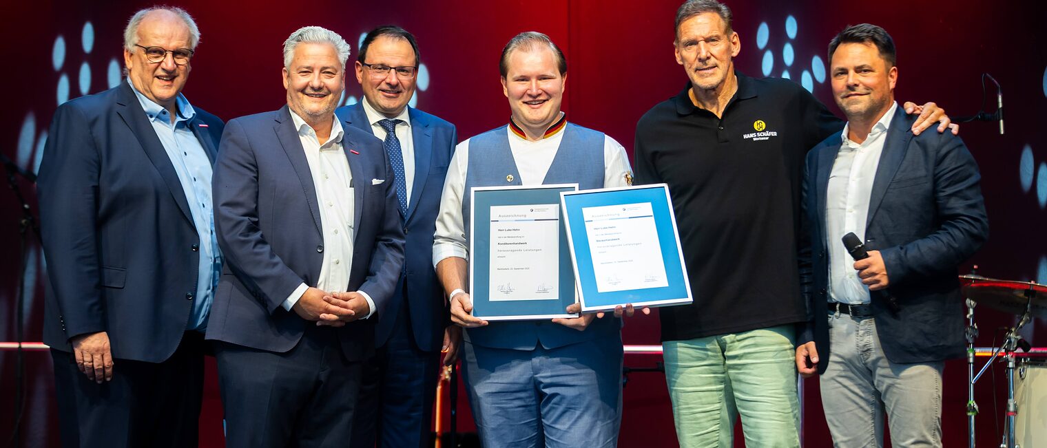 Bäcker- und Konditormeister Luke Hehn präsentiert seine zwei Bestenurkunden mit Reinhard Bauer, Matthias Graßmann, Martin Schöffel, Ralf Moeller und Andreas Grewe