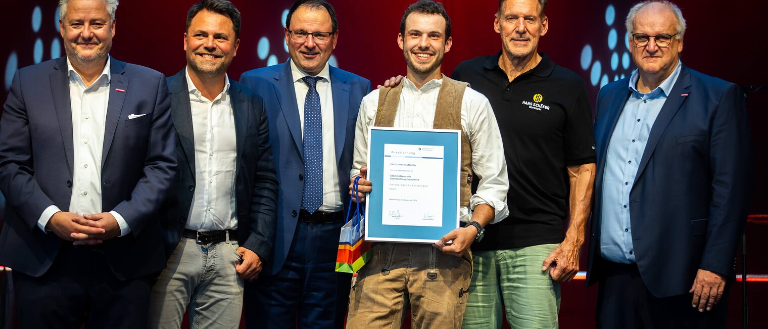 Steinmetzmeister Lukas Mutschler präsentiert seine Bestenurkunde mit Matthias Graßmann, Andreas Grewe, Martin Schöffel, Ralf Moeller und Reinhard Bauer