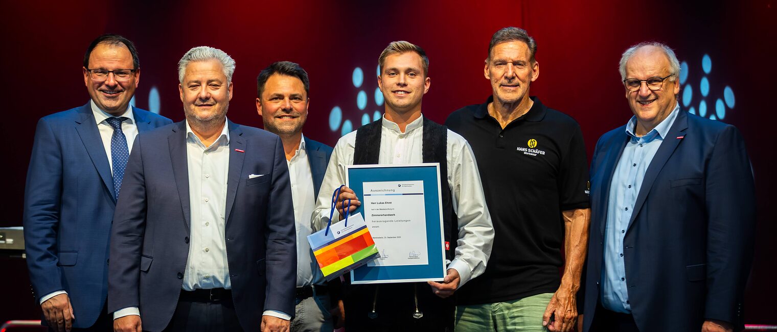 Zimmerermeister Lukas Ehret präsentiert seine Urkunde mit Martin Schöffel, Matthias Graßmann, Andreas Grewe, Ralf Moeller und Reinhard Bauer.