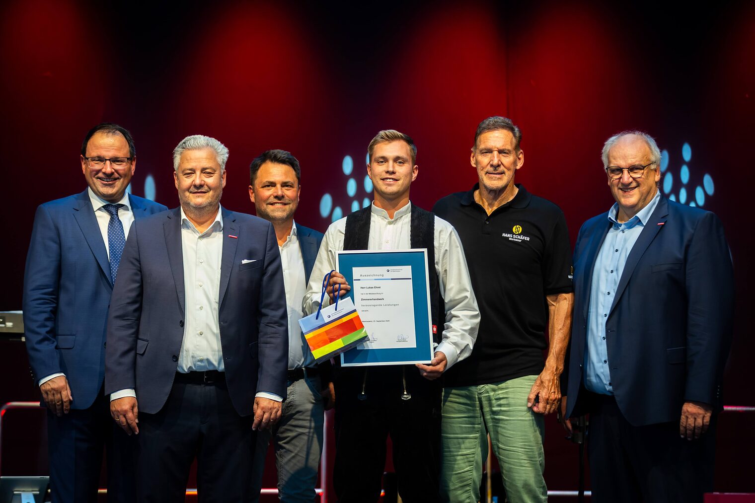 Zimmerermeister Lukas Ehret präsentiert seine Urkunde mit Martin Schöffel, Matthias Graßmann, Andreas Grewe, Ralf Moeller und Reinhard Bauer.