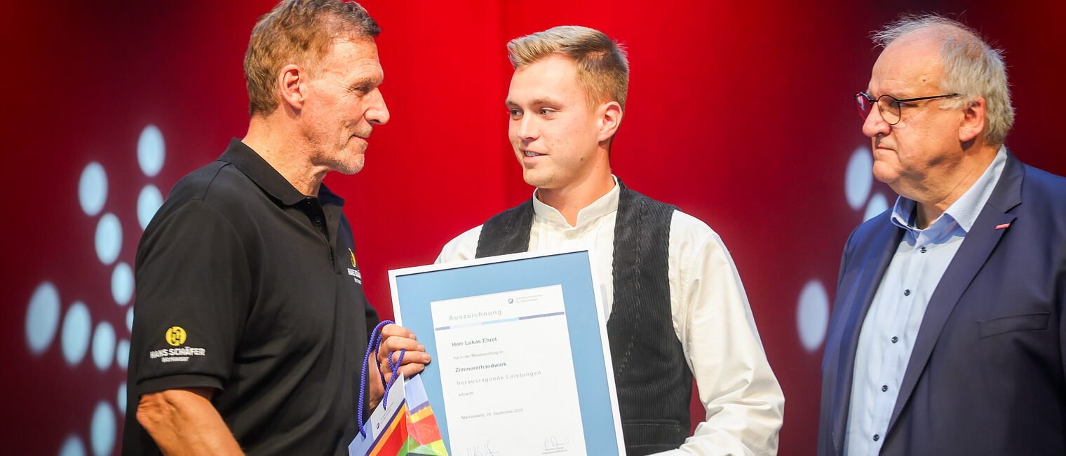 Lukas Ehret nimmt seine Urkunde von Ralf Moeller in Empfang.