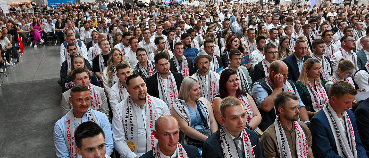 Die Meisterinnen und Meister sitzen in Reihen in der Glasschleif.