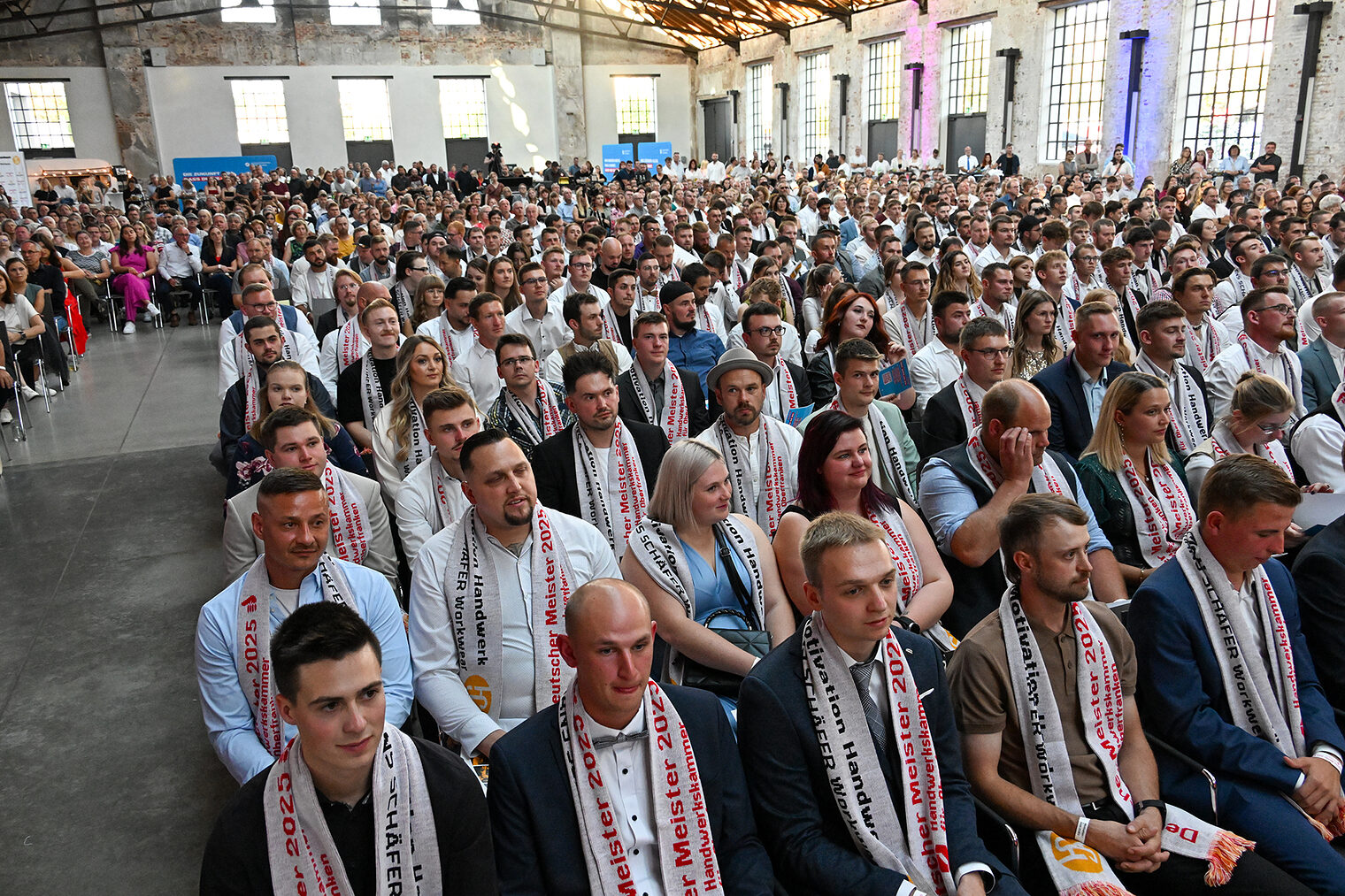 Die Meisterinnen und Meister sitzen in Reihen in der Glasschleif.