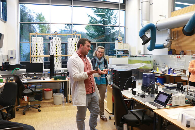 Simon Hehle zeigt den Besuchern im Technikraum einen Sensor für eine Tauchsonde.