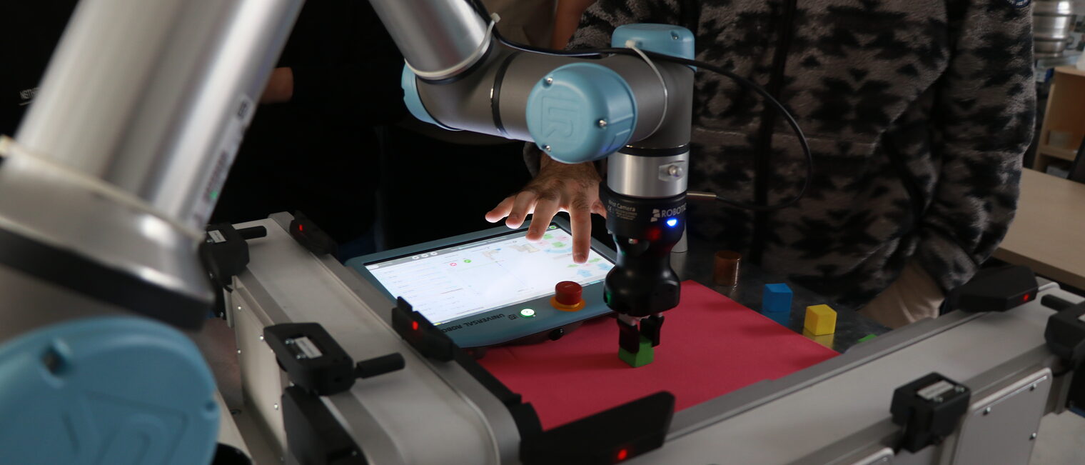 Nahaufnahme eines Roboterarms mit Tablet, der einen Testwürfel greift