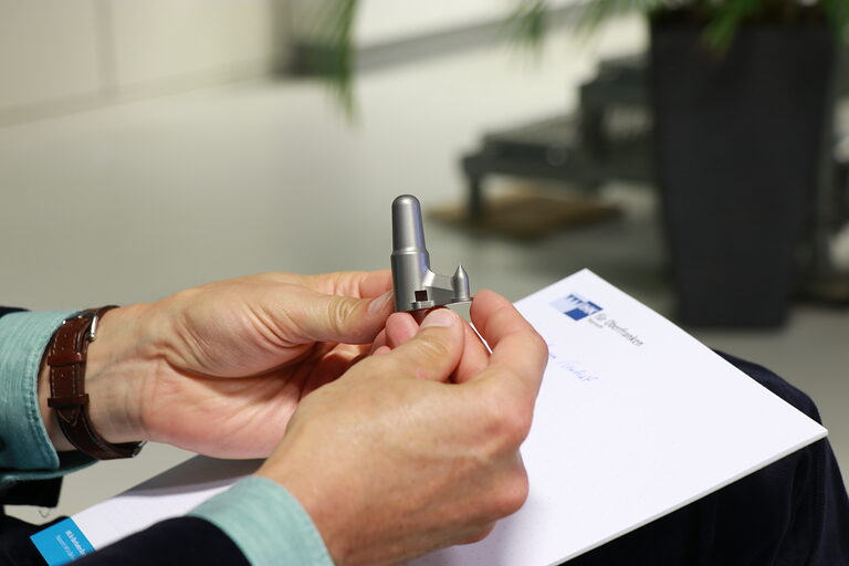 Eine Person hält eine Femur-Probe in der Hand.
