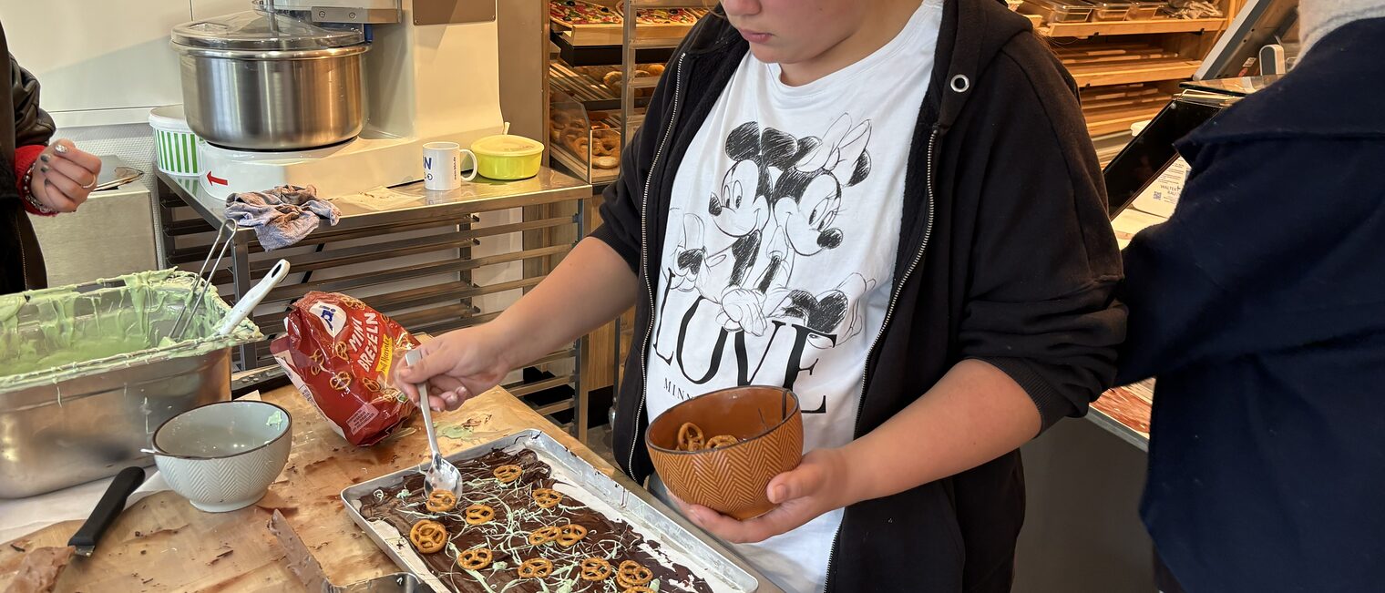 Eine Jugendliche garniert Bruchschokolade mit kleinen Salzbretzeln.