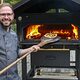 Ausbildungsmeister Ronny Vogel holt eine Pizza aus dem Holzofen.
