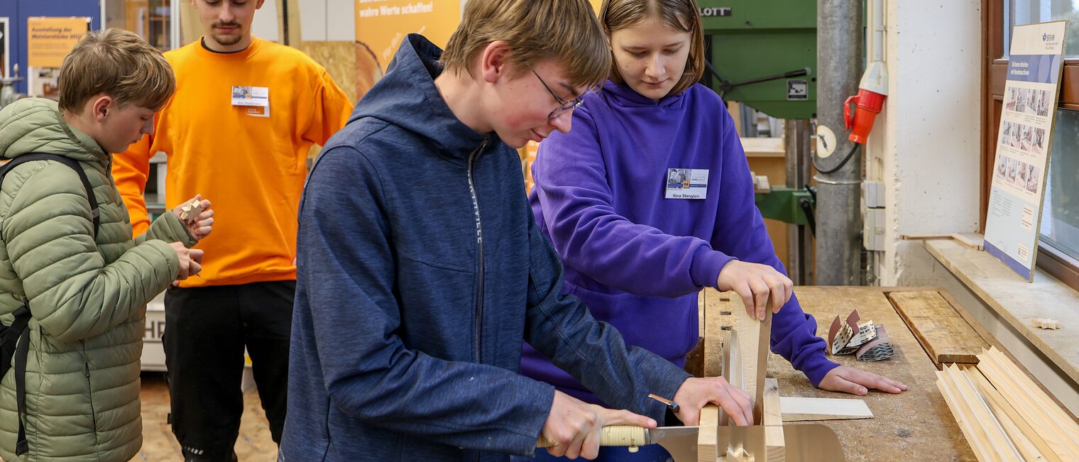Ein Jugendlicher sägt einen Holzstern von einem Balken ab.