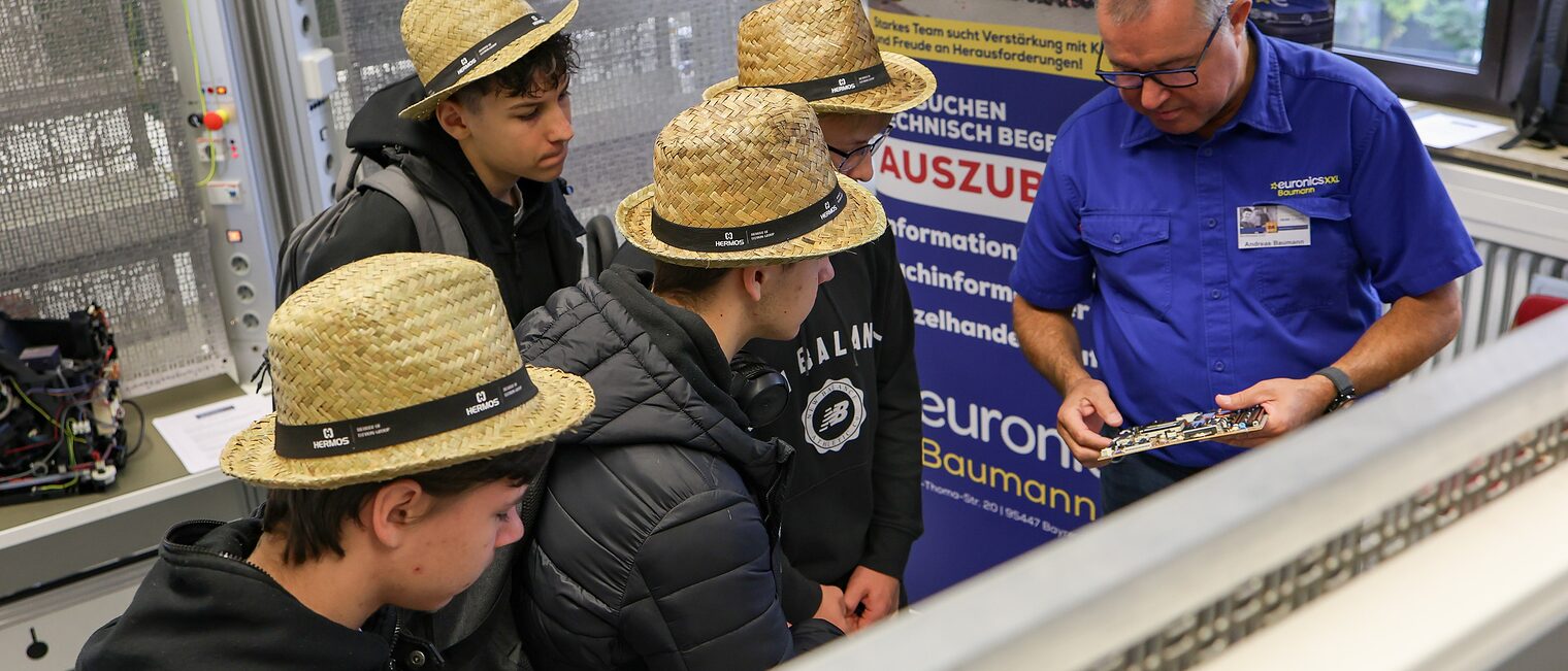 Ein Ausbilder zeigt Jugendlichen die Verkabelung eines Schaltkreises.