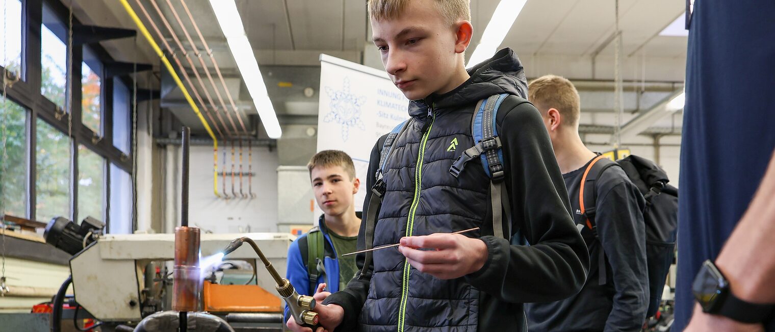 Ein Jugendlicher schweißt ein zwei Metallrohre zusammen.