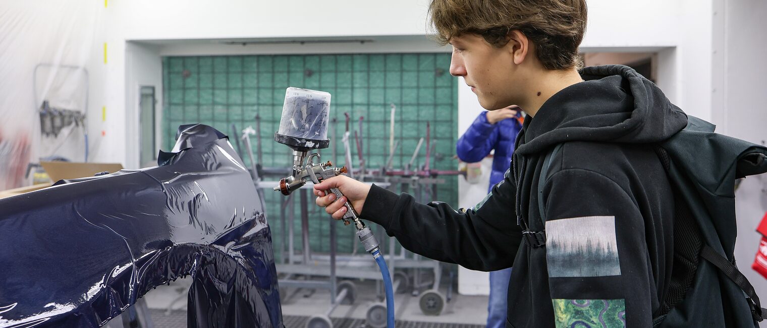 Ein Jugendlicher klemmt ein Industriekabel ab.