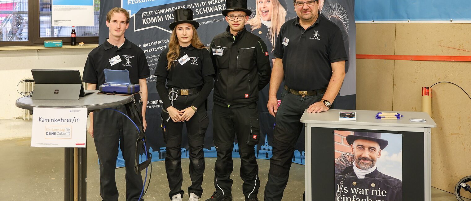 Das Team der Schornsteinfegerinnung steht an seinem Stand auf der Berufsmesse.
